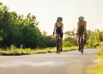 Couple riding bicycles outside of the city and wearing helmets and sunglasses