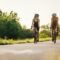 Couple riding bicycles outside of the city and wearing helmets and sunglasses